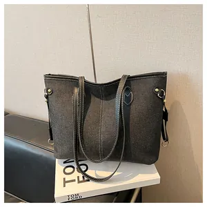 Detail of denim tote bag showing white contrast stitching and gold metal hardware accents