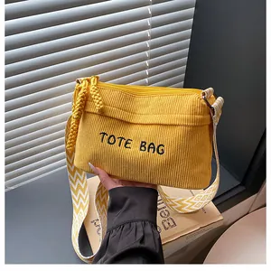 Detalle de bolso tote de pana amarilla con bordado TOTE BAG y correa con ondas