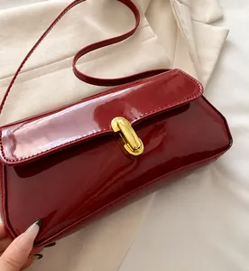 Close-up of bright red patent leather shoulder bag with golden metal buckle and clasp