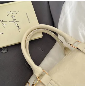 Detail der cremefarbenen Boston-Tasche mit Lychee-Leder und goldenen Metallbeschlägen