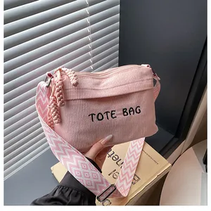 Detalle del bolso de pana rosa con bordado TOTE BAG y correa de hombro geométrica