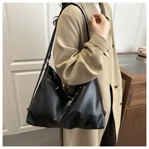 Close-up of black leather tote bag with soft matte finish and adjustable straps on a model