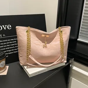 Detail of light pink tote bag with gold chain strap and deer pendant on a book