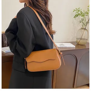 Détail du sac sous le bras marron caramel avec bord ondulé et bandoulière fine