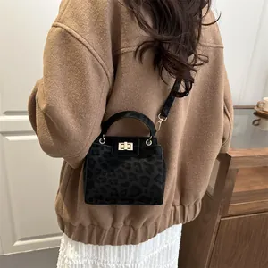 Detail of black leopard print crossbody bag featuring golden twist lock and top handle