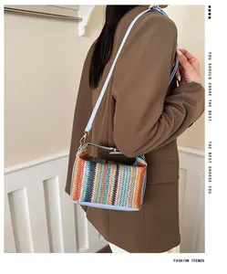Close-up of a striped woven crossbody bag with colorful rope texture and light blue leather strap