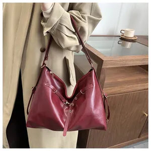 Detail of burgundy leather tote bag with metal ring accents styled with a khaki trench coat