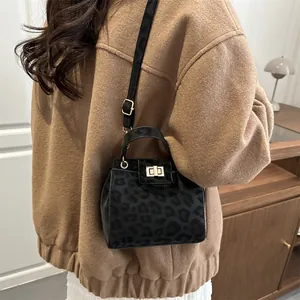 Detail of black leopard print crossbody bag with gold square metal twist lock on model