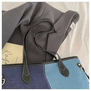 Close-up of contrast denim tote bag showing bicolor stitching and black leather handles