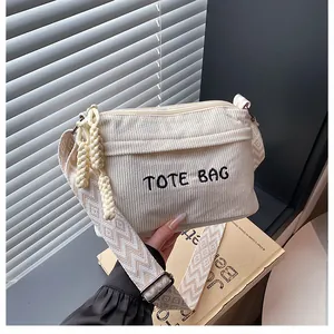 Detalle del bolso bandolera de pana con bordado TOTE BAG y correa de tejido geométrico