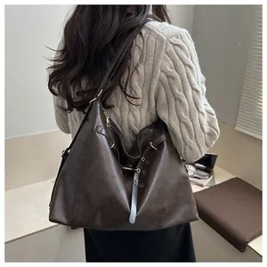 Detail of dark brown vintage leather tote bag with metallic eyelets and strap accents