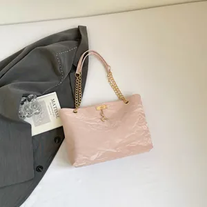 Detail of pink pleated tote bag featuring gold chain strap and elegant deer pendant charm