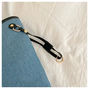 Close-up of blue denim tote bag with black leather trim and gold metal hardware