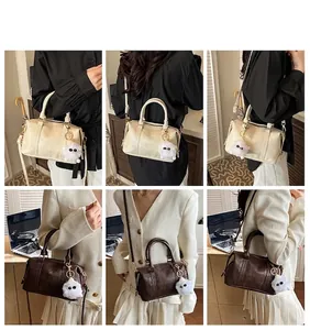 Detail of a Boston crossbody bag featuring a cream textured leather and plush charm