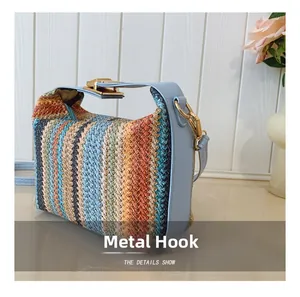 Detail of colorful woven straw bag featuring premium blue leather trim and golden metal hooks