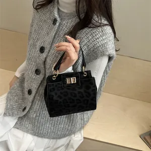 Detail of black leopard print crossbody bag with golden clasp and leather handle