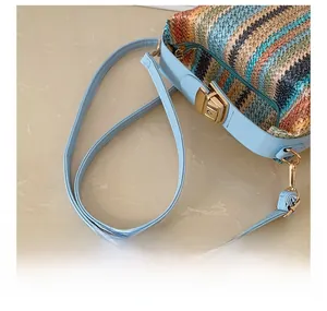 Detail of adjustable blue strap and colorful striped woven straw bag with gold buckle