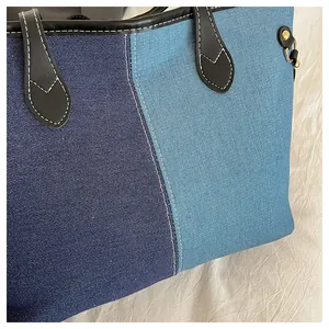 Detail of high-capacity denim tote bag with contrast stitching and blue patchwork design