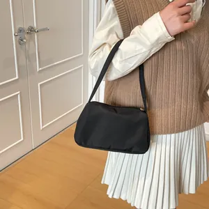Minimalist black nylon shoulder bag for women shown worn as an underarm bag style