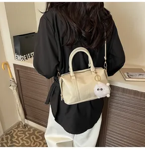 Detail der cremefarbenen Boston Bag mit Prägung und Plüsch-Anhänger an einem Model