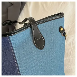 Detail of patchwork denim tote bag with black leather handles and gold metal hardware