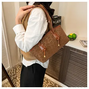 Dettaglio della borsa shopper leopardata con logo GILLAIBI e manici in pelle marrone