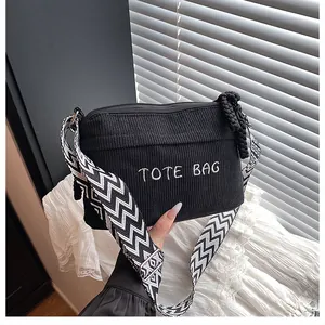Detalle del bolso tote de pana negra con bordado TOTE BAG y correa de hombro tejida