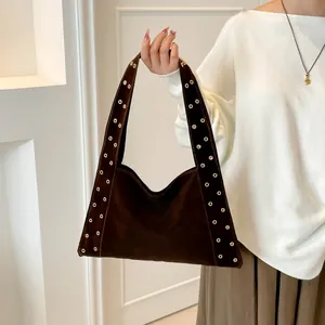 Détail du sac bandoulière en daim marron foncé avec des rivets métalliques sur les côtés