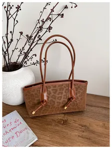 Detail of leopard print tote bag with gold hardware on a dark wood surface