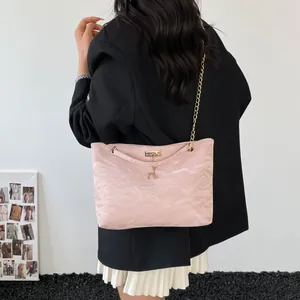Light pink chain shoulder bag with gold deer charm worn by a model in black blazer