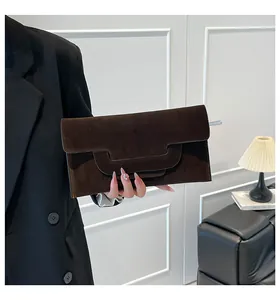 Detail of dark brown suede envelope clutch featuring a unique geometric cutout flap design