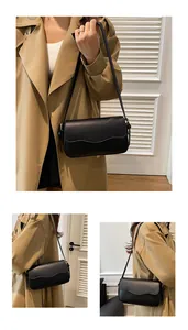 Détail d'un sac bandoulière noir en cuir minimaliste avec rabat aux bords ondulés