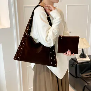 Sac fourre-tout en daim marron avec œillets dorés et pochette sur un mannequin
