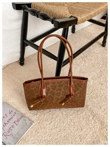 Detail of leopard print tote bag with thin knotted handles and premium textured finish