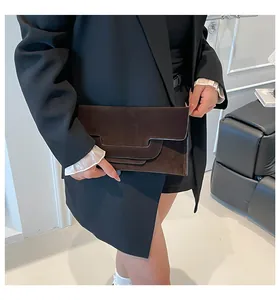 Detail of dark brown suede envelope clutch with geometric trapezoid flap design