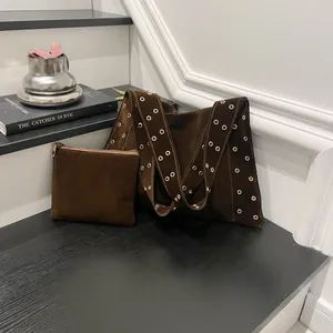 Détails du sac cabas en daim marron foncé avec œillets métalliques argentés sur la bandoulière