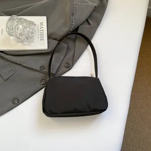 Minimalist black rectangle nylon shoulder bag displayed with professional props