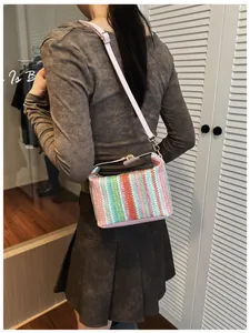 Detailed view of colorful striped woven crossbody bag with pink leather strap on shoulder