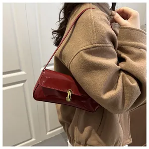 Detalle de bolso baguette en charol burdeos con cierre giratorio dorado en modelo