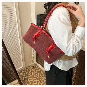 Dettaglio della borsa tote leopardata bordeaux con manici rossi e nodo decorativo