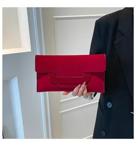 Detail of red envelope clutch bag featuring velvet texture and unique arc-shaped handle