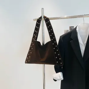 Détail du sac cabas en daim marron avec œillets métalliques argentés sur la bandoulière