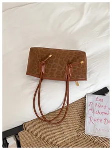 Close-up of leopard print tote bag texture with brown leather trim and gold hardware