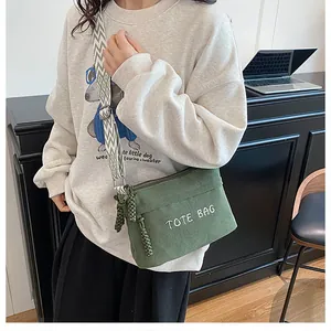 Detalle de bolso tote de pana verde con bordado TOTE BAG y correa geométrica en modelo