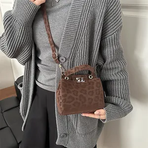 Detail of a brown leopard print crossbody bag with silver twist lock on a fashion model