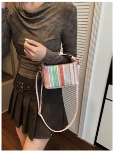 Detail of colorful striped woven straw handbag with pink leather straps and gold buckle