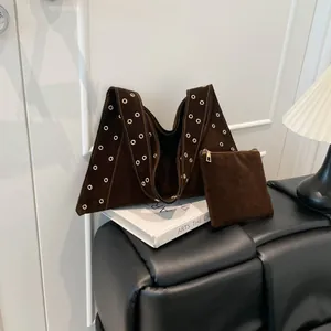Détail d'un sac cabas en daim marron foncé avec œillets dorés et pochette assortie