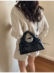 Rear view of a black PU leather crossbody bag with bow accents and slim shoulder strap