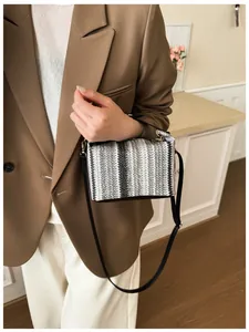 Detail of hand-woven crossbody bag with black, white, and grey textured pattern