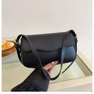 Sac à bandoulière chic en cuir noir mat avec rabat incurvé et détails dorés